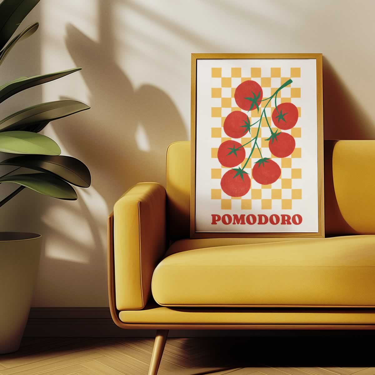A framed art print featuring red tomatoes on a yellow-and-white chequered background with the word 'POMODORO' at the bottom, leaning against a yellow sofa in a sunlit room with a potted plant nearby.